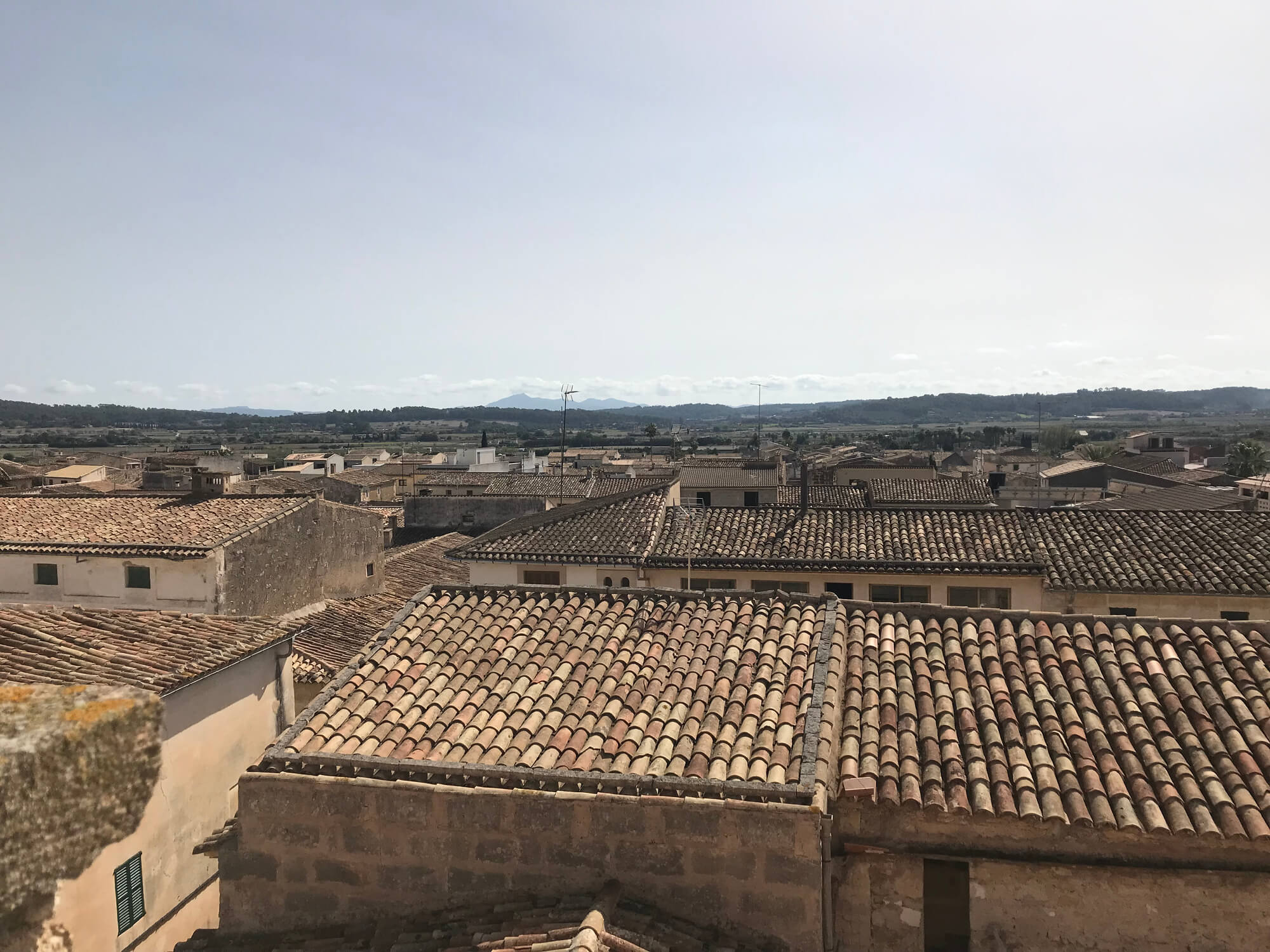 Traditional clay tile rooftops in Mediterranean village with mountains in background