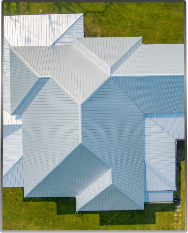 Aerial view of modern house with complex metal roof geometry and green lawn