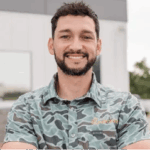 Smiling man in camouflage polo shirt with beard and curly hair outdoors