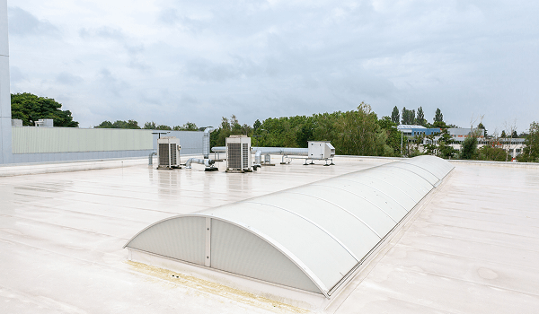 Rooftop with HVAC units and skylight on a cloudy day.